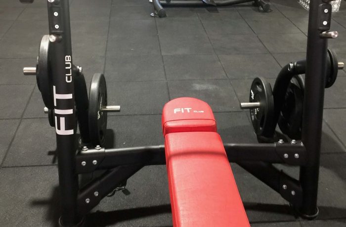 Red bench press station with barbell and weight plates