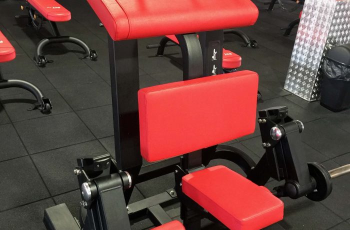 Red padded strength machine beside weight plates