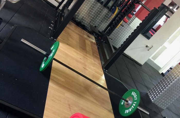 Weightlifting platform and barbell beside the lifting rack
