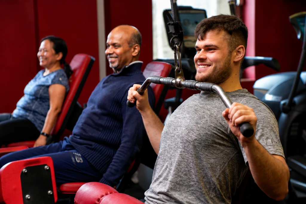 Three members exercising on different pin-loaded resistance machines at Fit Club Northwood Hills