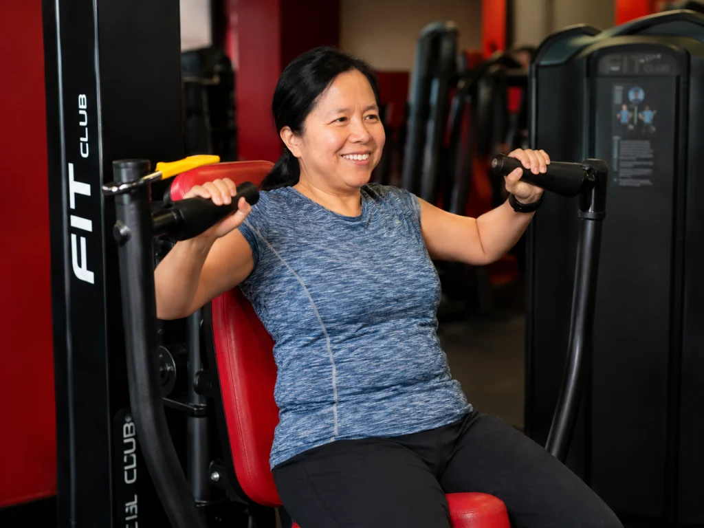 Lady using a pin-loaded chest press at Fit Club Northwood Hills