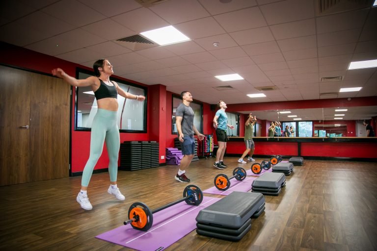 Members exercising with barbells and steps during FIT Pump at Fit Club Northwood Hills