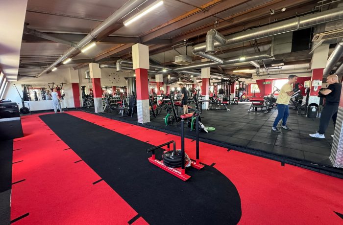 Weighted sled on the red and black sprint track beside the strength area at Fit Club Northwood Hills