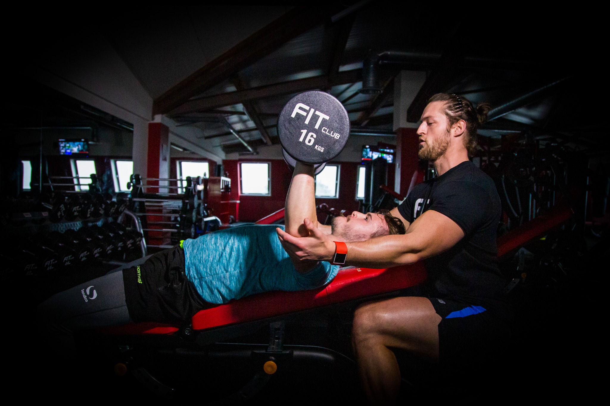 Personal Trainer assisting a member with a dumbbell bench press at Fit Club Northwood Hills