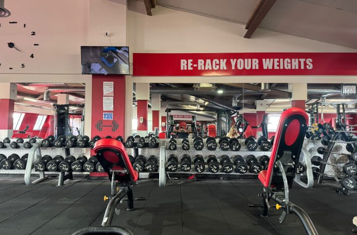 Dumbbell racks and adjustable benches in front of mirrors at Fit Club Northwood Hills